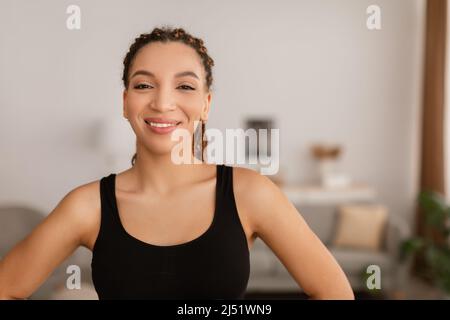 Allegra ragazza del fitness nera che posa indossando il Fitwear a casa Foto Stock