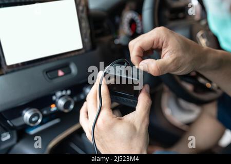 Mano del tecnico che prepara e installa il registratore auto con telecamera anteriore all'interno dell'auto Foto Stock