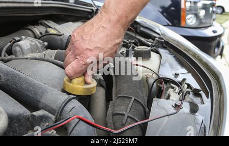 L'operatore svitate il tappo dell'olio sul motore della vettura. Operatore meccanico Foto Stock