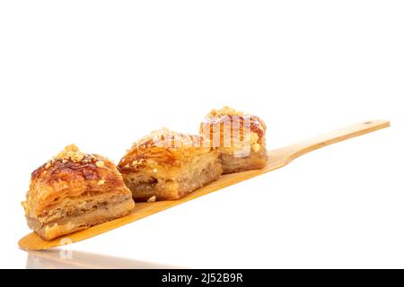 Dolce baklava classico con cucchiaio di legno, macro, isolato su sfondo bianco. Foto Stock