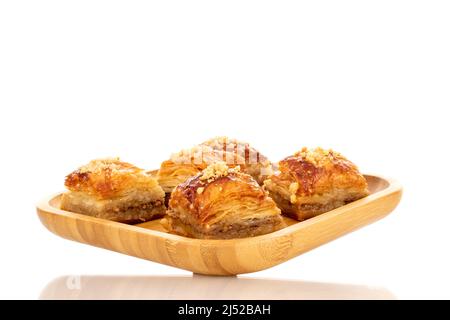 Dolce baklava classico su un vassoio di bambù, macro, isolato su sfondo bianco. Foto Stock