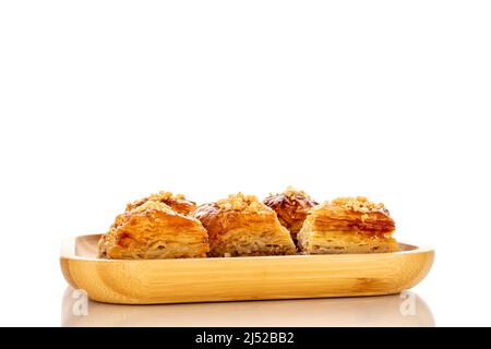 Dolce baklava classico su un vassoio di bambù, macro, isolato su sfondo bianco. Foto Stock