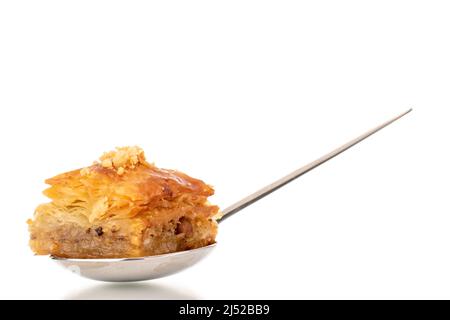 Dolce baklava classico con cucchiaio di metallo, macro, isolato su sfondo bianco. Foto Stock