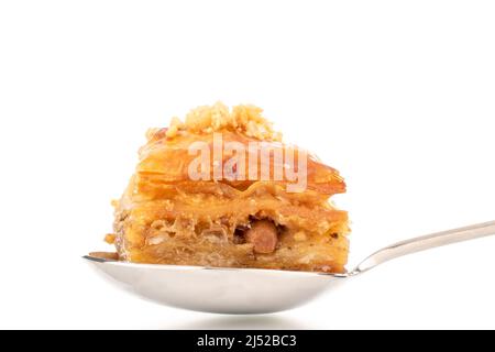 Dolce baklava classico con cucchiaio di metallo, macro, isolato su sfondo bianco. Foto Stock