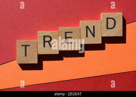 Tendenza, parola in lettere di legno alfabeto isolato su sfondo rosso e arancione come titolo banner Foto Stock