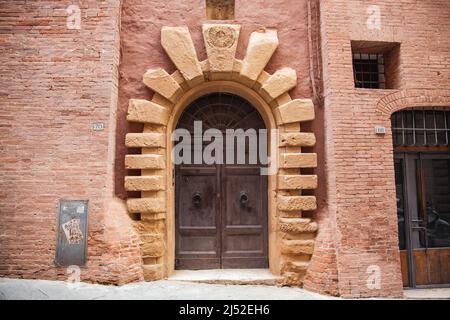 Antica porta medievale in legno con decorazioni nella città di Siena Foto Stock