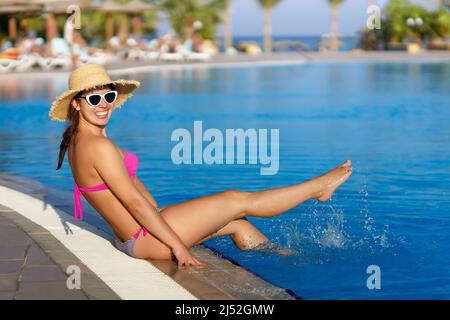 bella giovane donna in cappello di paglia in piscina Foto Stock