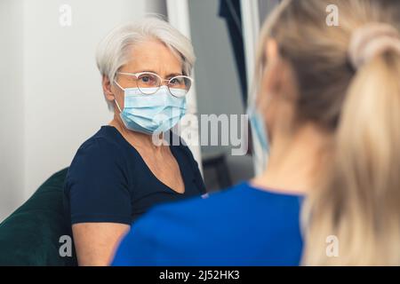 donna anziana visitata dallo specialista di assistenza domiciliare durante il concetto di assistenza sanitaria di stanza vivente di closeup medio pandemico. Foto di alta qualità Foto Stock