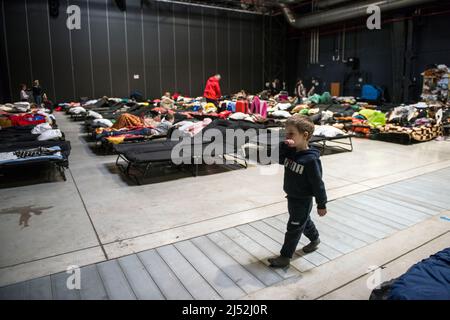 Varsavia, Polonia. 19th Apr 2022. Un bambino sta camminando vicino ai letti del centro di accoglienza dei rifugiati Global Expo a Varsavia. Secondo le stime dell'UNHCR, l'agenzia delle Nazioni Unite per i rifugiati, cinque milioni di ucraini sono partiti da quando la Russia ha invaso l'Ucraina il 24th febbraio. Quasi tre milioni di persone hanno attraversato il confine polacco dall’Ucraina. A Varsavia, ancora migliaia di persone si trovano nel centro di accoglienza Global Expo per i rifugiati, uno dei tanti e secondi rifugi per rifugiati della capitale. (Foto di Attila Husejnow/SOPA Images/Sipa USA) Credit: Sipa USA/Alamy Live News Foto Stock