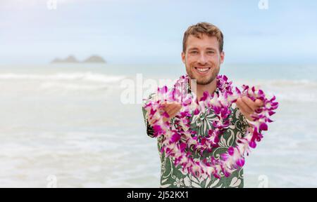 Le Hawaii accolgono l'uomo caucasico in camicia hawaiana che accoglie il turista dando lei di fiori freschi come gesto di spirito aloha sulla spiaggia delle Hawaii per il luau party Foto Stock