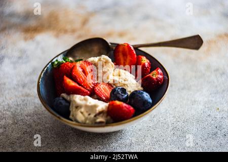 Ciotola di gelato alla vaniglia con mirtilli freschi e fragole Foto Stock