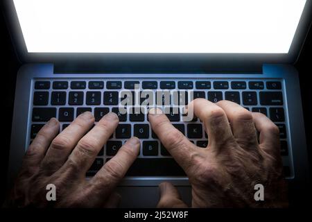 Dettaglio delle mani che digitano sulla tastiera del computer con schermo luminoso Foto Stock