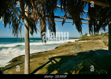 Punto di riferimento storico Windansea Surf Shack adiacente alle onde e surf lungo la spiaggia in una luminosa giornata di sole a Windansea Beach, la Jolla, California, USA Foto Stock