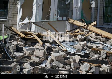 Pezzi e frammenti di mura giacciono vicino alla casa dopo l'esplosione di una conchiglia in Ucraina Foto Stock