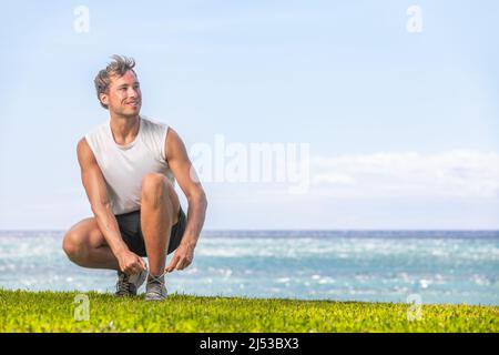 Uomo sano felice che si prepara a camminare o a fare jogging sulla spiaggia estiva - stile di vita attivo per la perdita di peso runner andare fuori Foto Stock