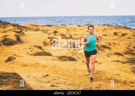Uomo running atleta maschile runner cross country corsa sulla costa di sabbia dorata da oceano. Giovani uomini che si allenano a fare jogging sul sentiero all'aperto Foto Stock