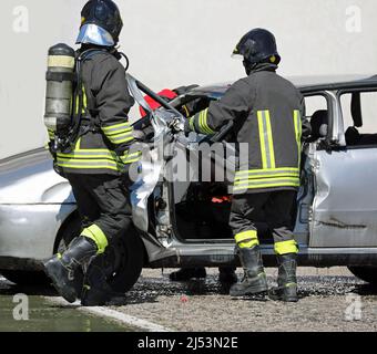 vigili del fuoco con bombola di ossigeno durante l'intervento di soccorso della persona gravemente ferita a causa dell'incidente stradale sulla strada Foto Stock