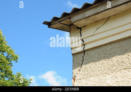 Dettaglio architettonico di danneggiato angolo casa dilatato vecchio edificio facciata muro. Riparazione del tetto. Foto Stock