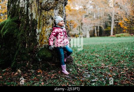 Una ragazza getta un sacco di foglie di acero giallo Foto Stock