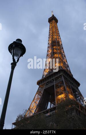 Parigi, Francia: Una lampada da strada e la Torre Eiffel, torre di metallo completata nel 1889 per l'esposizione universale, visto illuminato in una serata nuvolosa Foto Stock