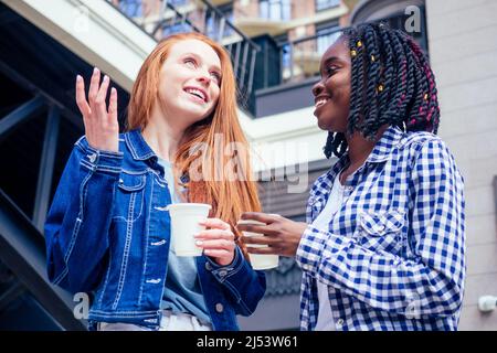 Felice Brightful positivo momenti di due ragazze alla moda bere caffè per andare e parlare Foto Stock