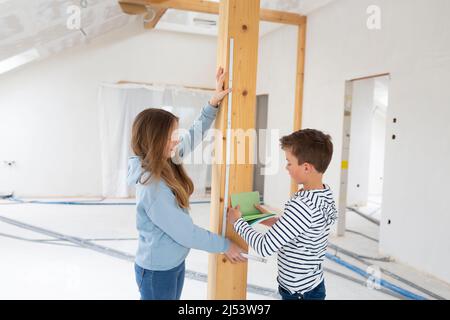 Fratello e sorella sono sul sito di costruzione della loro nuova camera loft appartamento con carte colore e la regola pieghevole e misurare tutto Foto Stock