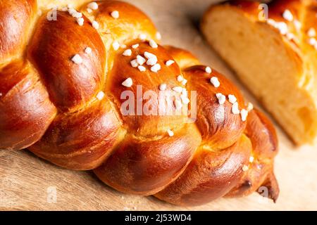 Bel pane dorato cotto a tre treccia con uova lavate e zucchero di grandine. Challah è un pane speciale di origine ebraica Ashkenazi, solitamente intrecciato e typi Foto Stock