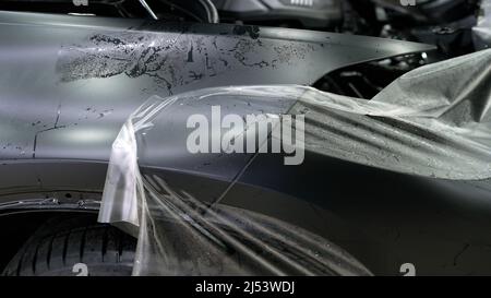 La pellicola protettiva per l'auto è stata staccata. Pellicola protettiva per il corpo di un'auto durante il servizio di assistenza. Foto Stock