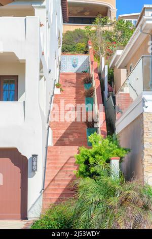 Scale rosse di cemento all'esterno dell'edificio con piante in vaso su ogni pianerottaggio Foto Stock