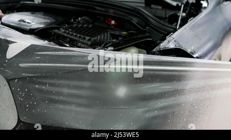 La pellicola protettiva per l'auto è stata staccata. Pellicola protettiva per il corpo di un'auto durante il servizio di assistenza. Foto Stock
