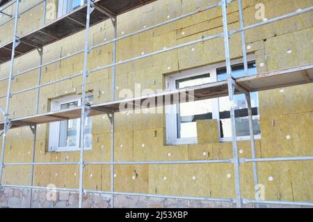 Installare l'isolamento in lana minerale di roccia. Efficienza energetica casa ristrutturazione muro per il risparmio energetico. Esterno casa muro isolamento termico con woo minerale Foto Stock