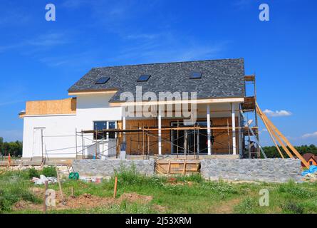 Ristrutturare e riparare la facciata della casa residenziale con isolamento in lana minerale, intonacatura, parete di pittura. Costruzione di una casa con scandole di asfalto ro Foto Stock