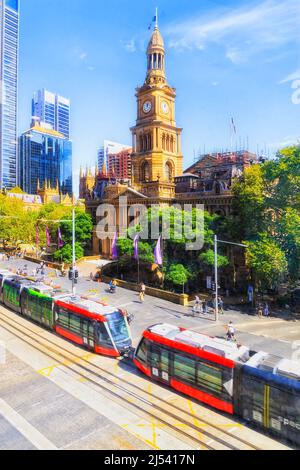 Tram con trasporto pubblico che attraversa george Street Square di fronte alla casa del Municipio di Sydney. Foto Stock