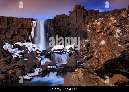 Bellissimo paesaggio dall'Islanda. Öxarárfoss cascata prima dell'alba. Acqua nella roccia. Scena invernale con neve, pietra e cascata. Vacanze invernali Foto Stock