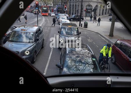 I pedoni attraversano la strada e un ciclista passa auto e taxi che si estendono in lontananza, visto dal ponte superiore di un autobus di Londra ad Aldwych, il 13th aprile 2022, a Londra, Inghilterra. Foto Stock