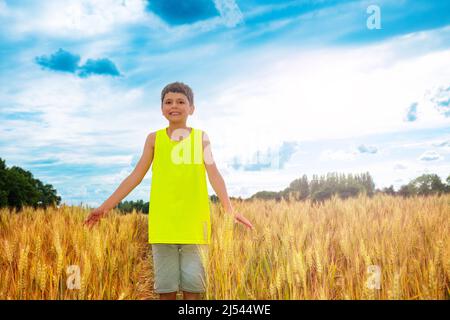 Ragazzo stare in piedi nel campo di grano con le mani sollevate Foto Stock