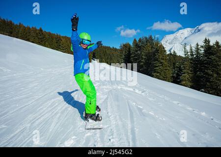 Ragazzo scivolo veloce sullo snowboard dalla montagna, vista frontale Foto Stock