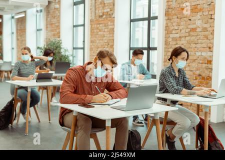 Gli studenti multietnici stanno scrivendo in quaderni Foto Stock