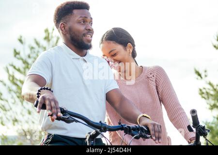 Donna vietnamita e uomo afroamericano che prende una bicicletta a noleggio Foto Stock