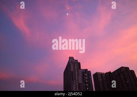 Romantico cielo al tramonto sulla città con un luminoso quarto di luna Foto Stock