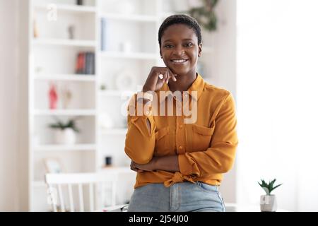 Giovane donna di affari nera di successo che si pone in ufficio Foto Stock