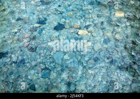 Letto di ciottoli del fiume visto attraverso acqua di colore turchese increspata chiaro - sfondo naturale Foto Stock