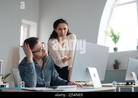 Dispiaciuti boss femmina che scolding sconvolto subordinati, indicando a errore nel progetto di business in ufficio Foto Stock