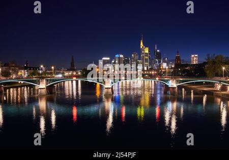 Skyline di Francoforte e ponte illuminato Ignatz Bubis che si riflette nel fiume meno di notte Foto Stock