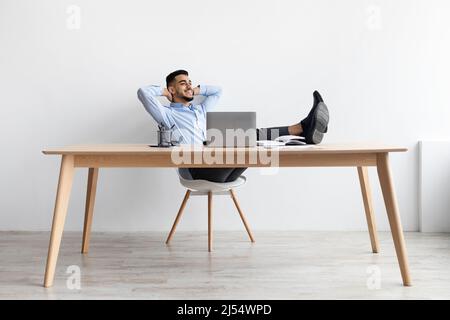Un uomo arabo sorridente che si appoggiava alla scrivania Foto Stock