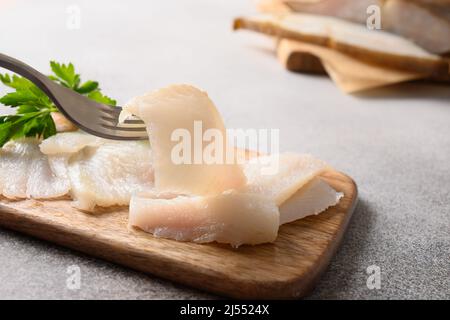 Fette di halibut affumicate su sfondo grigio. Uomo che mangia pesce prelibato. Primo piano. Ricco di grassi sani omega 3 insaturi per chiarezza mentale. Cervello Foto Stock