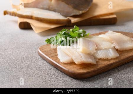 Pesce prelibato halibut affumicato servito con prezzemolo per mangiare sul tagliere di legno. Primo piano. Ricco di grassi sani omega 3 insaturi. Foto Stock