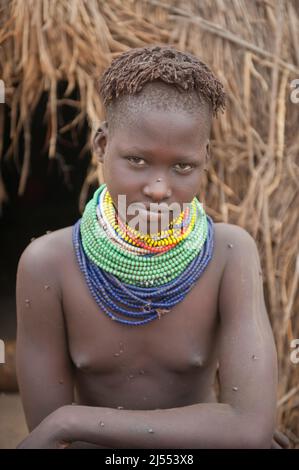 Nyangatom (Bumi) ragazza con pile di perle nella parte anteriore del suo rifugio, Omo river Valley, Etiopia Foto Stock