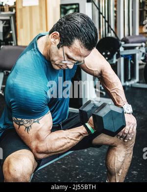 Stock Foto di un uomo del muscolo bicipite treni con manubri in palestra. Centro fitness Foto Stock