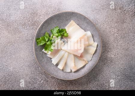 Deliziose fette di halibut affumicate servite in piatto bianco isolato su sfondo grigio. Vista dall'alto. Grassi insaturi omega 3 sani. Foto Stock